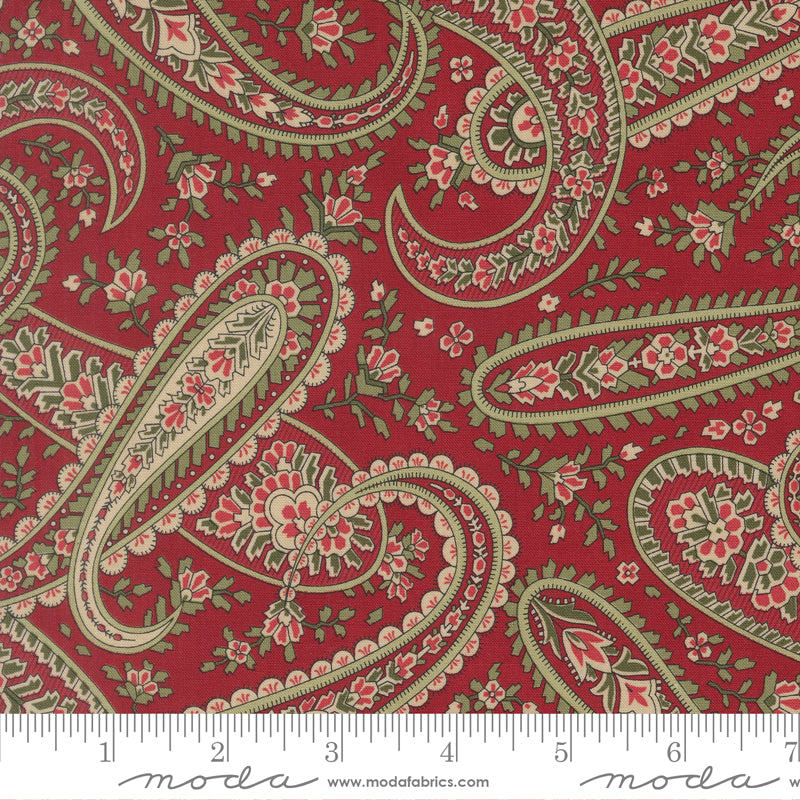Paisley pattern fabric swatch with a ruler for scale on a red background