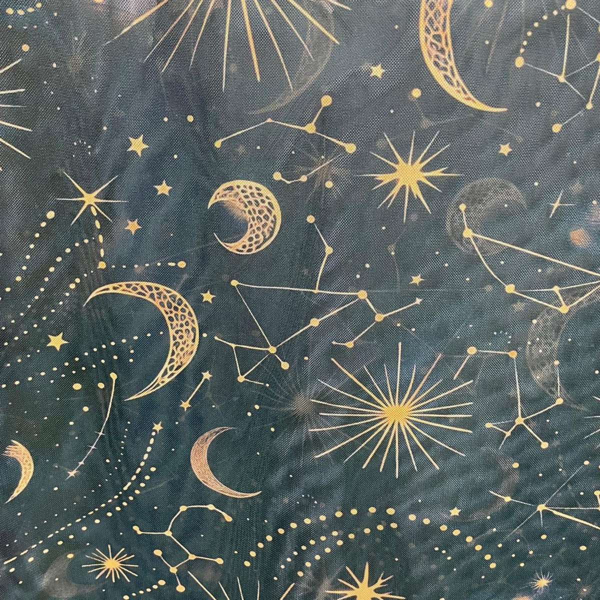 Dark teal fabric featuring a repeating celestial pattern of gold crescent moons, stars, and constellations.