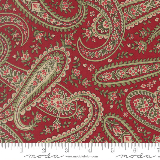 Paisley pattern fabric swatch with a ruler for scale on a red background