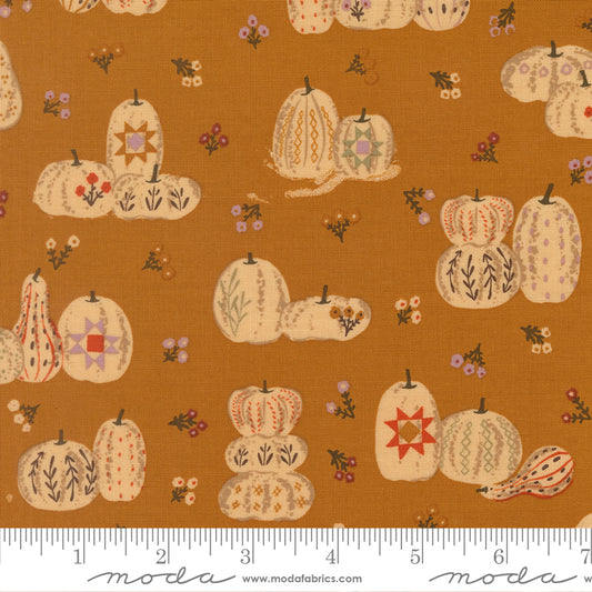 Fabric with pumpkins and gourds pattern on a brown background, featuring ruler.