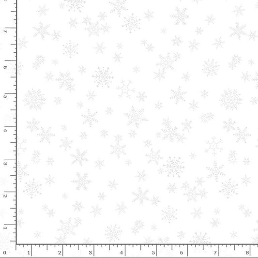 White fabric with a repeating pattern of light gray snowflakes, shown with a ruler on the left and bottom edges to indicate scale.